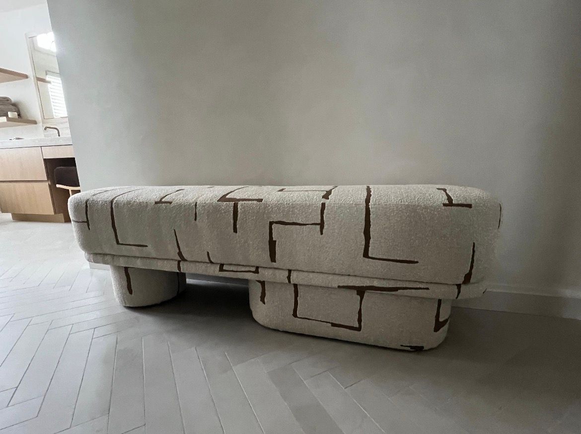 Kitchen island with gray countertop and cushioned bench; light blue cabinets; checkered floor.