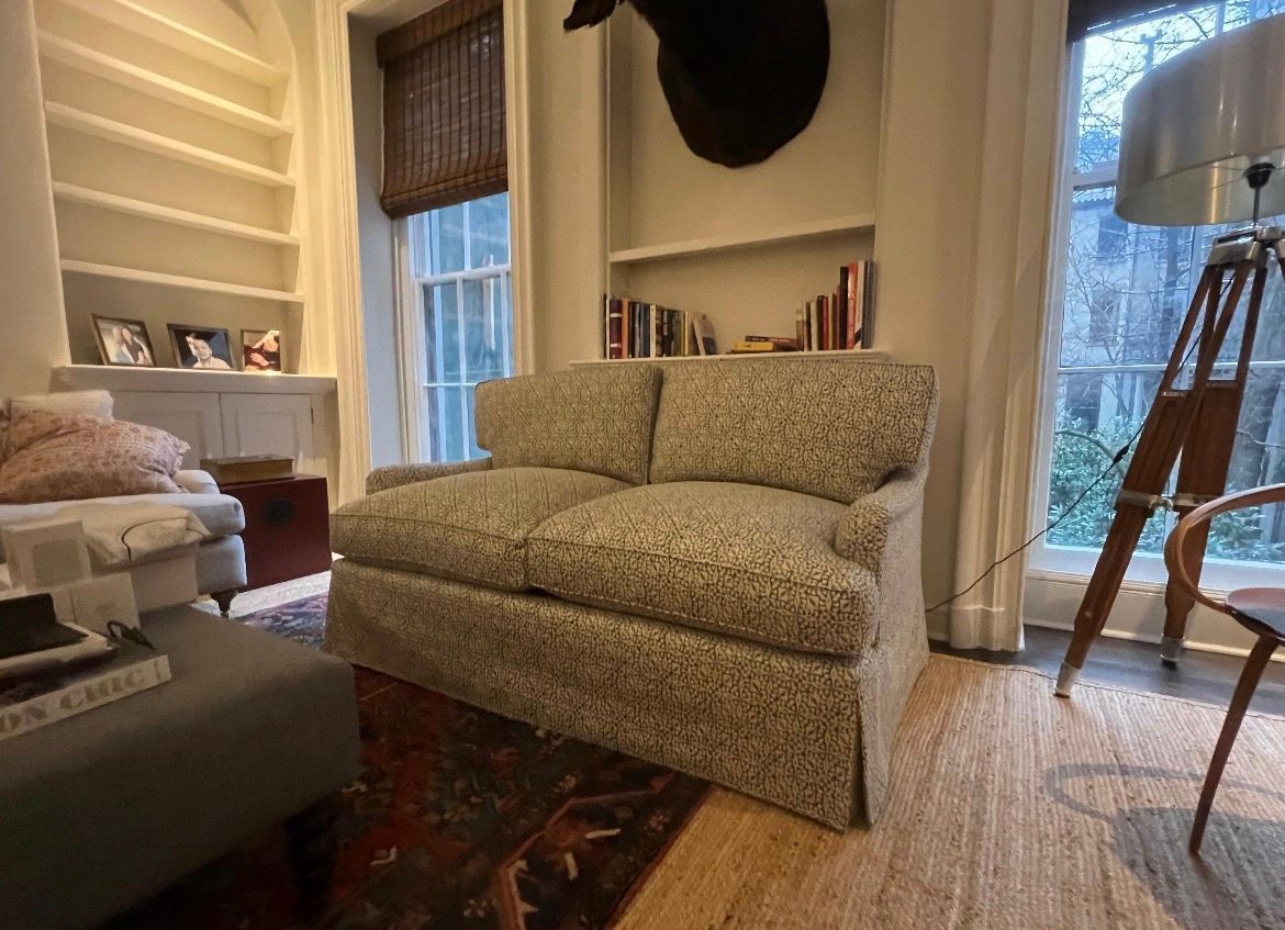 Living room with sofa, bookshelves, window, floor lamp, and a deer head mount.