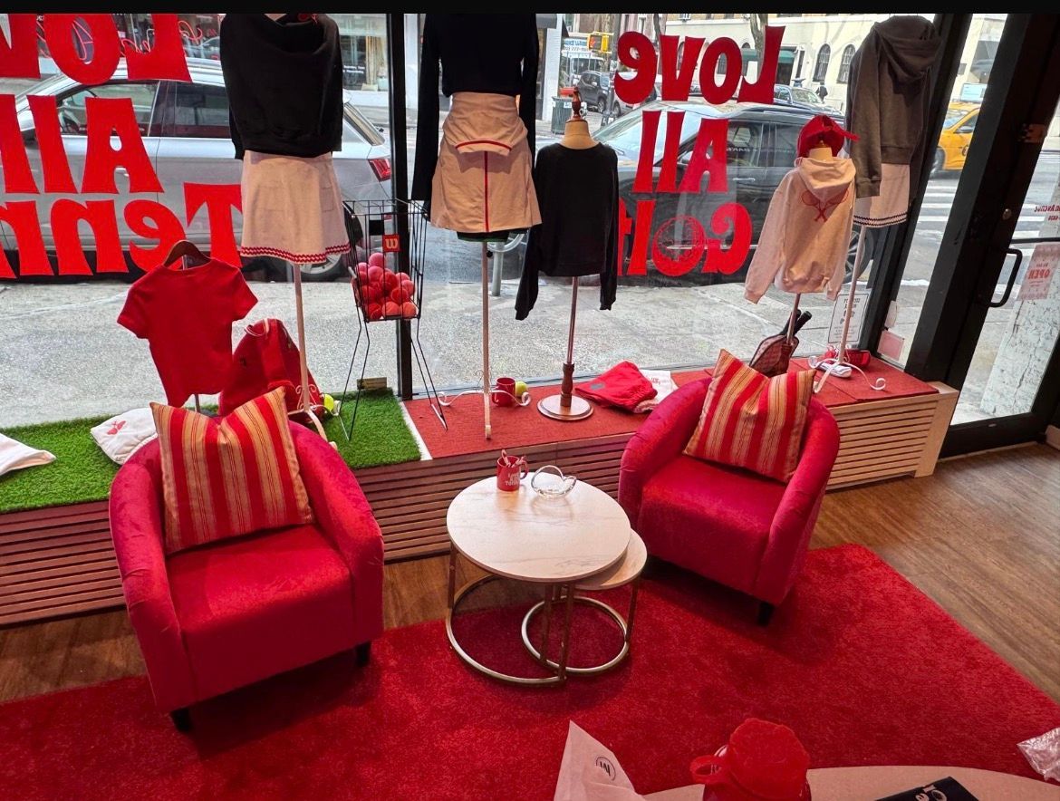 Red clothing store display with armchairs, rugs, mannequins, and text 