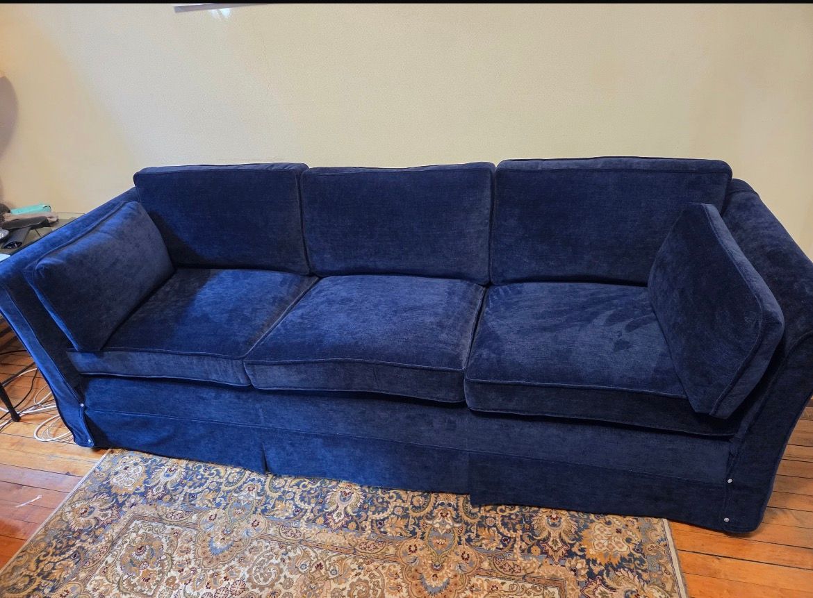 Blue upholstered sofa on a patterned rug.