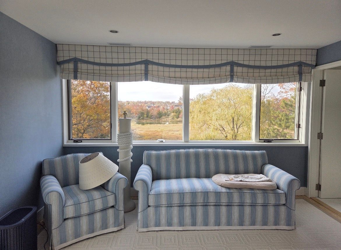 Room with blue striped sofa and chair, window with outdoor view, blue walls and valance.