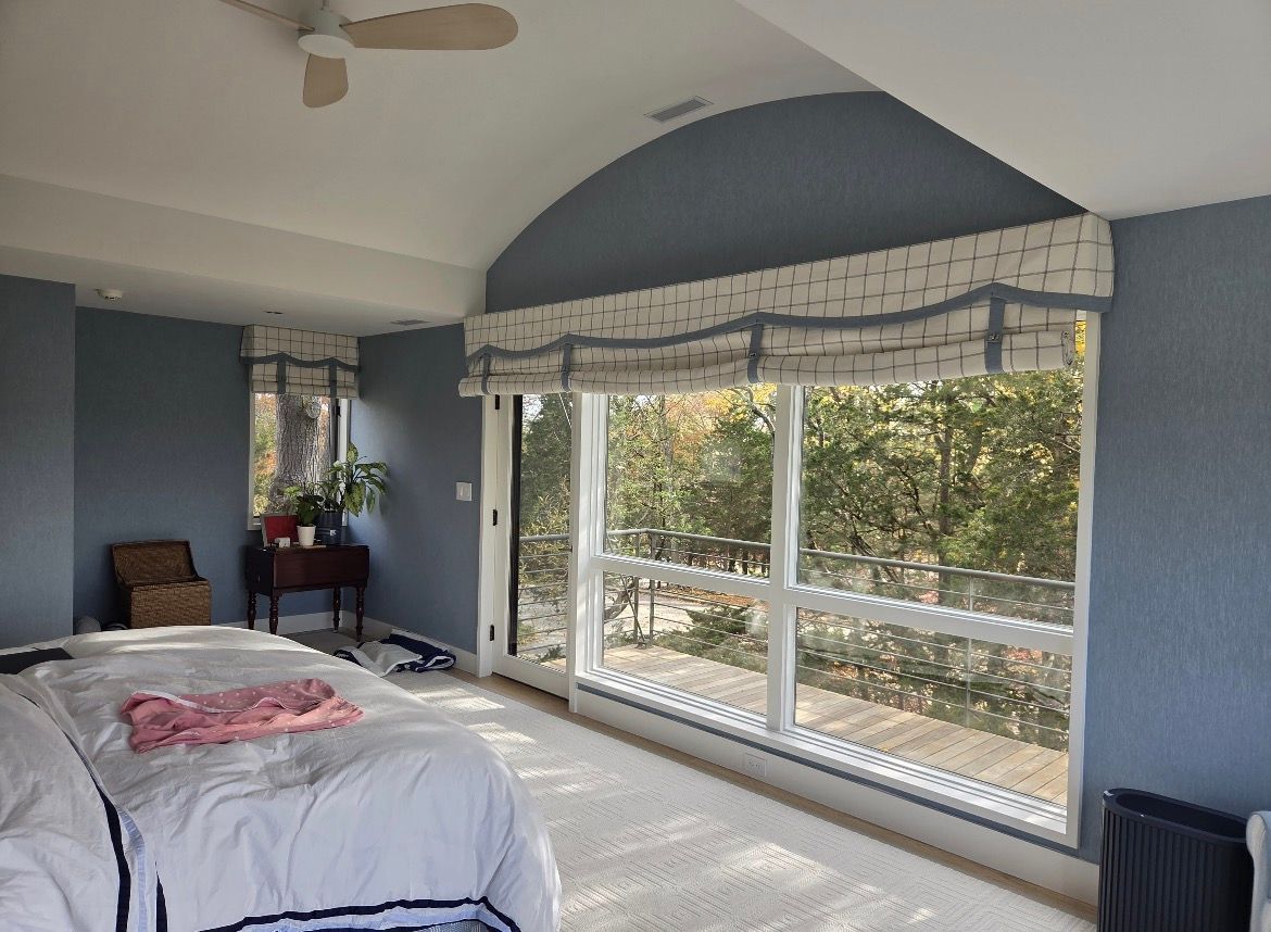 Bedroom with blue walls, large windows, and a decorative valance.