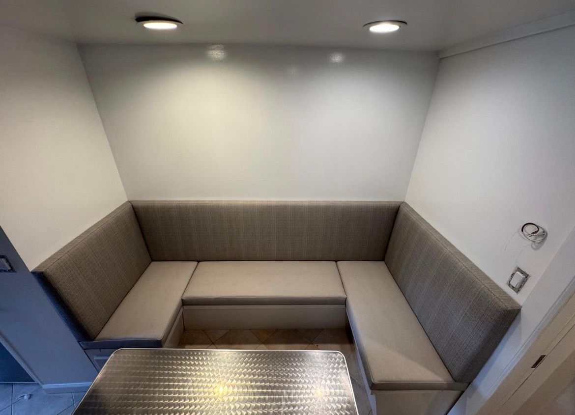U-shaped booth seating with light gray cushions in a built-in nook, with overhead lighting.