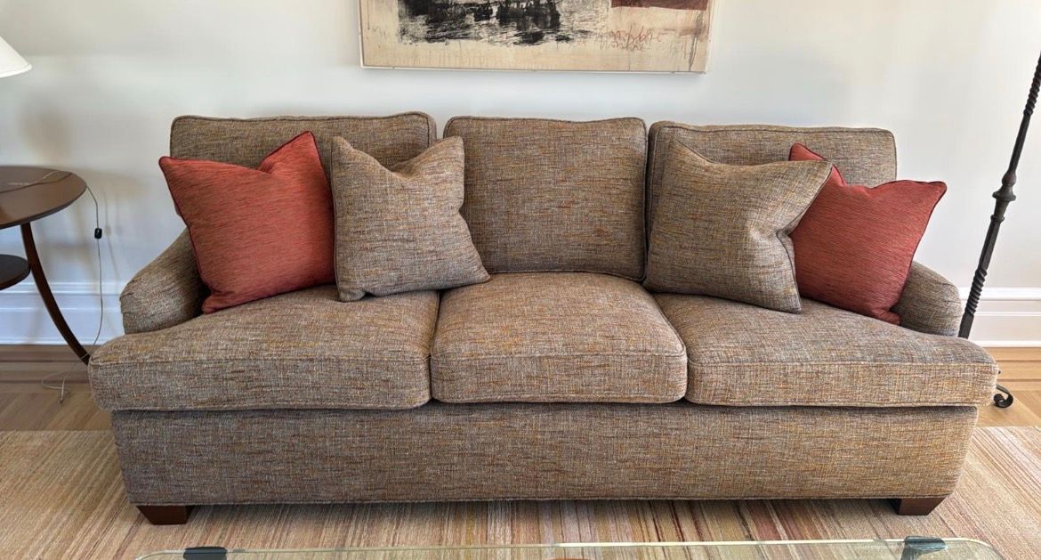 Brown tweed sofa with terracotta pillows in a living room.