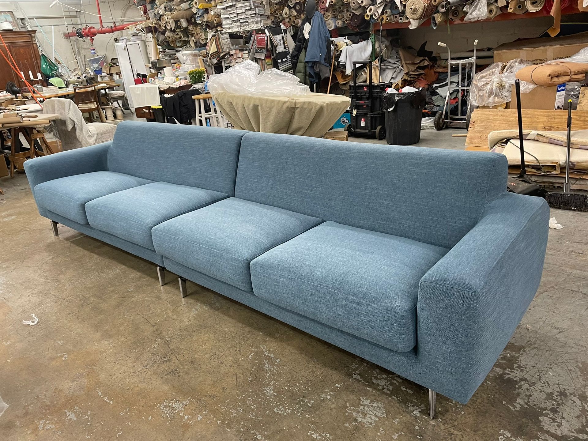 Blue, modern sofa with chrome legs in a workshop.