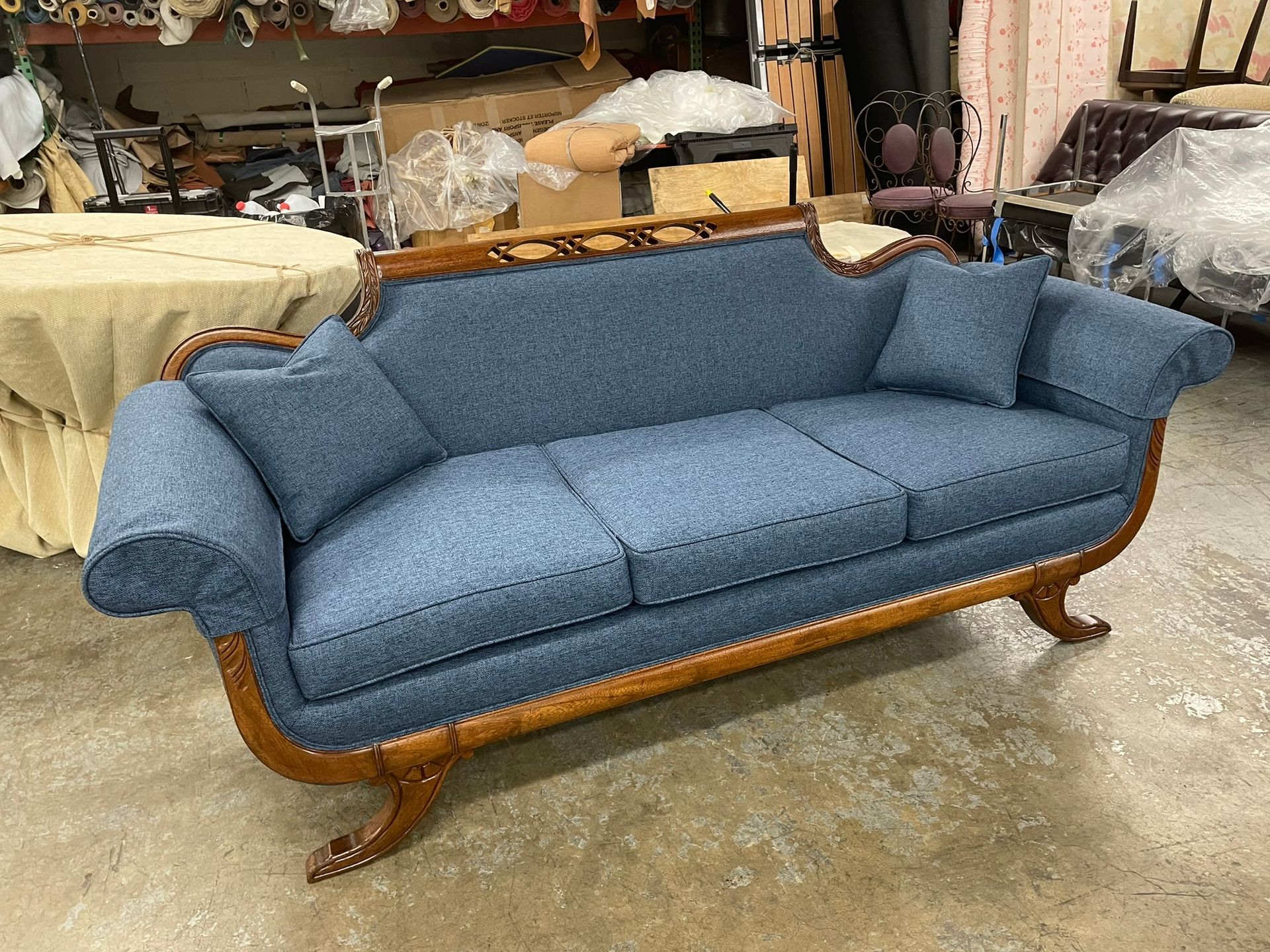 Blue upholstered sofa with wood trim in a workshop.