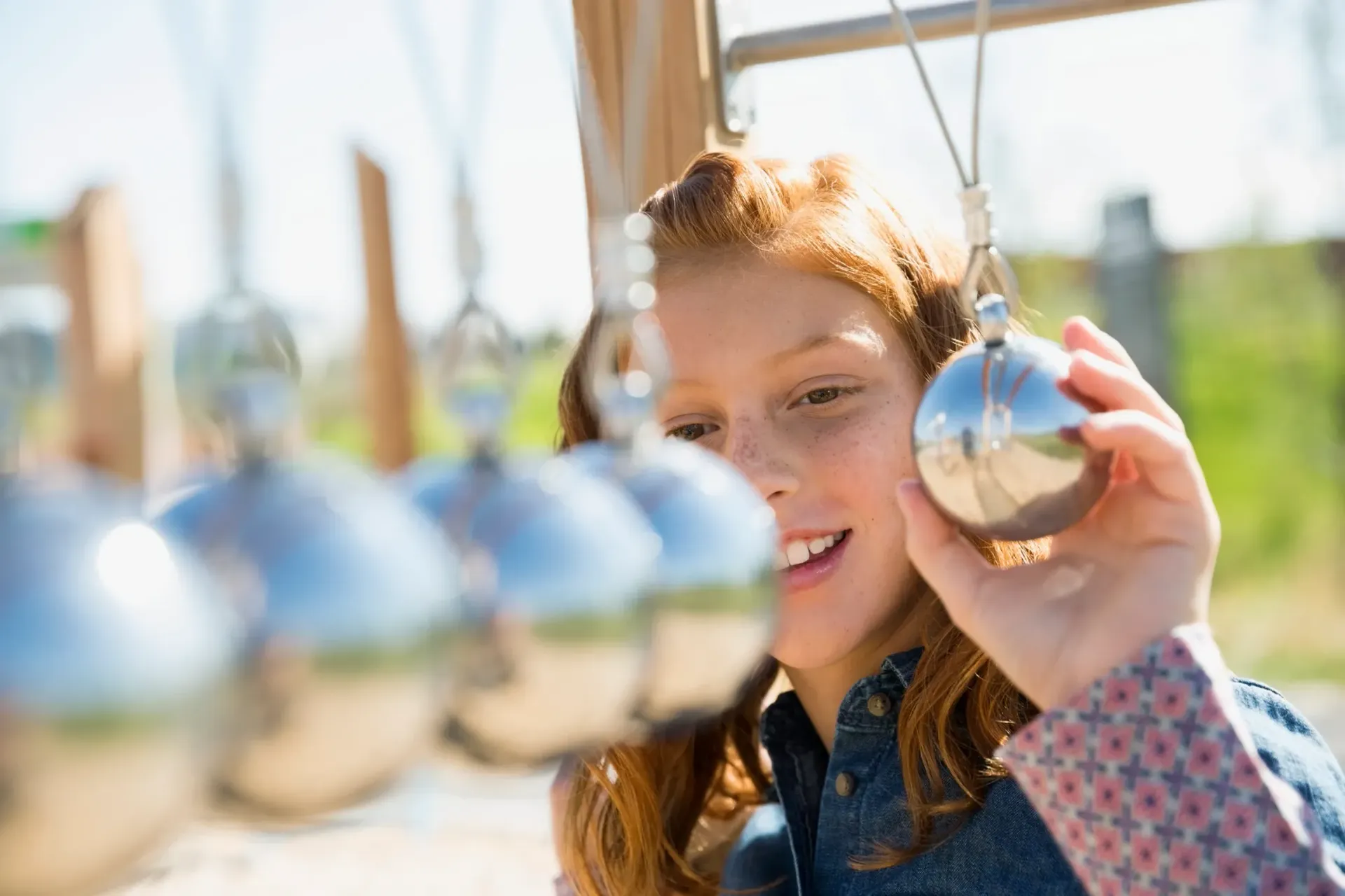 A young girl is playing with a pendulum in a playground.