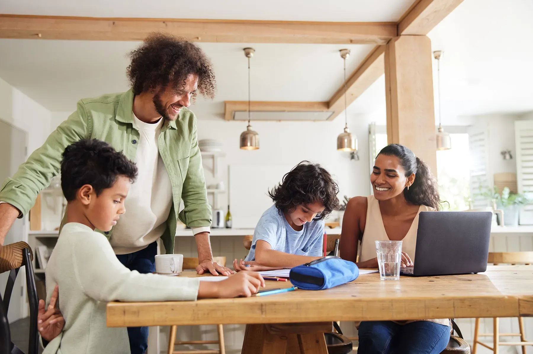 A family is sitting at a table with a laptop.