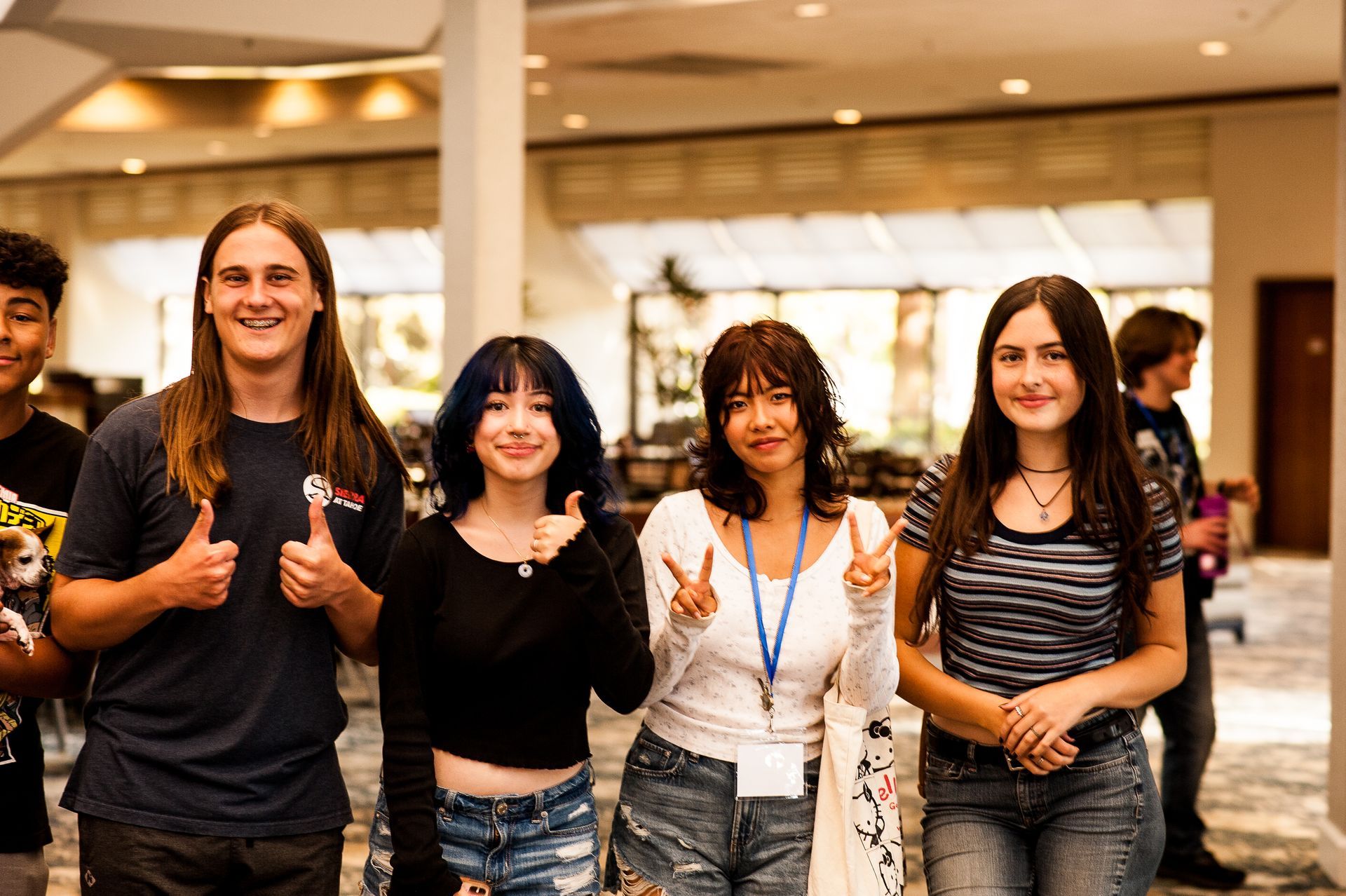 A group of young people are posing for a picture and giving a thumbs up.