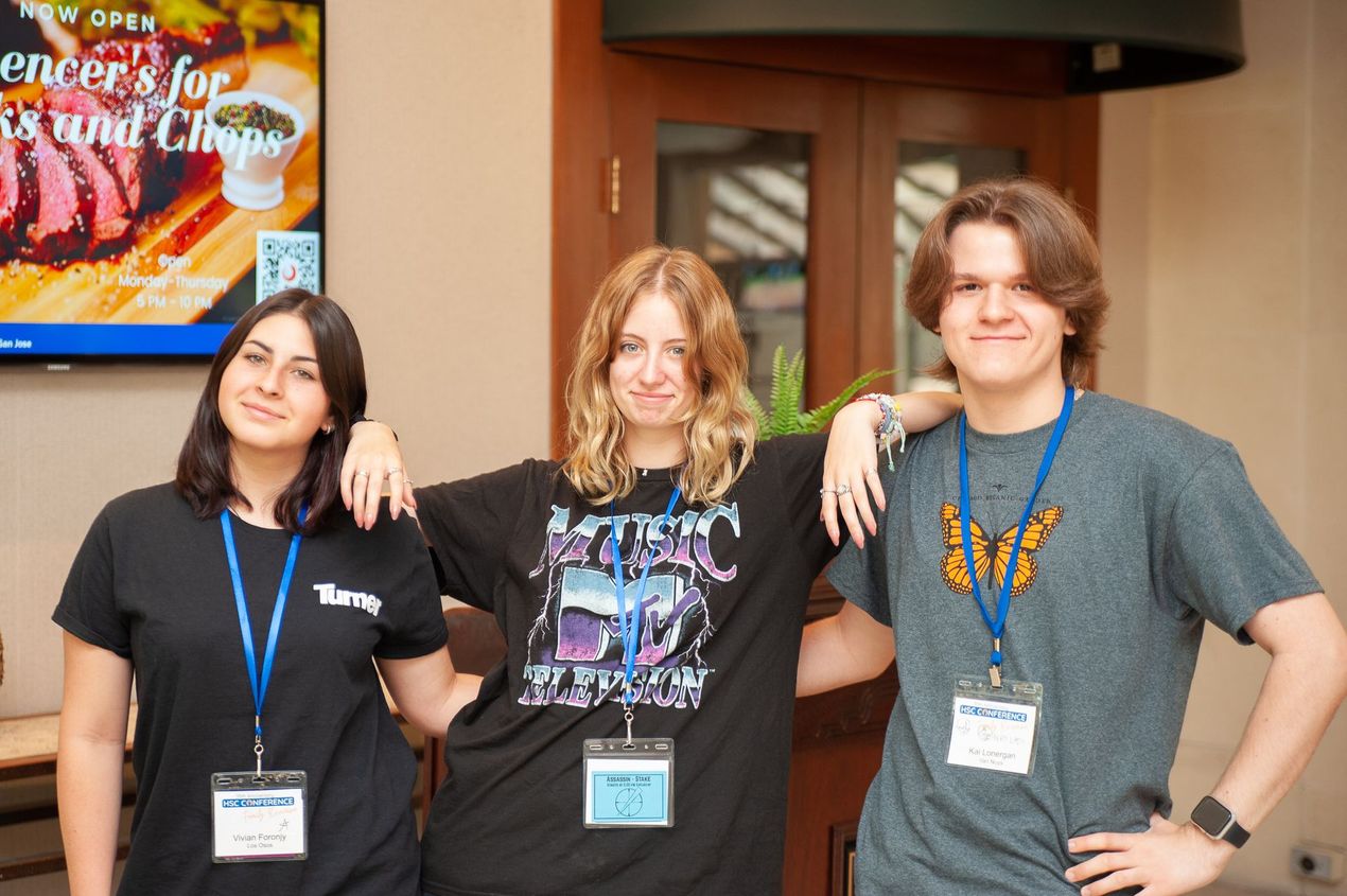 Three people are posing for a picture in front of a sign that says ' spencer 's for sound clips '.