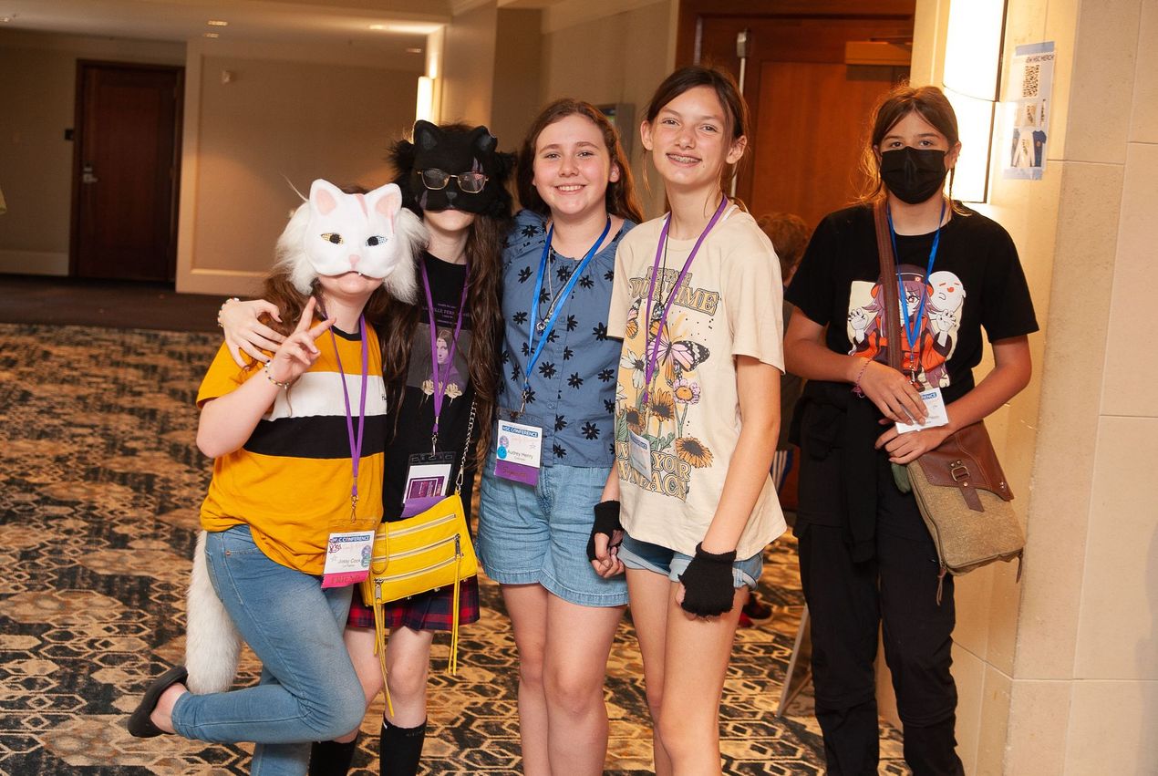 A group of young girls are posing for a picture in a hallway.