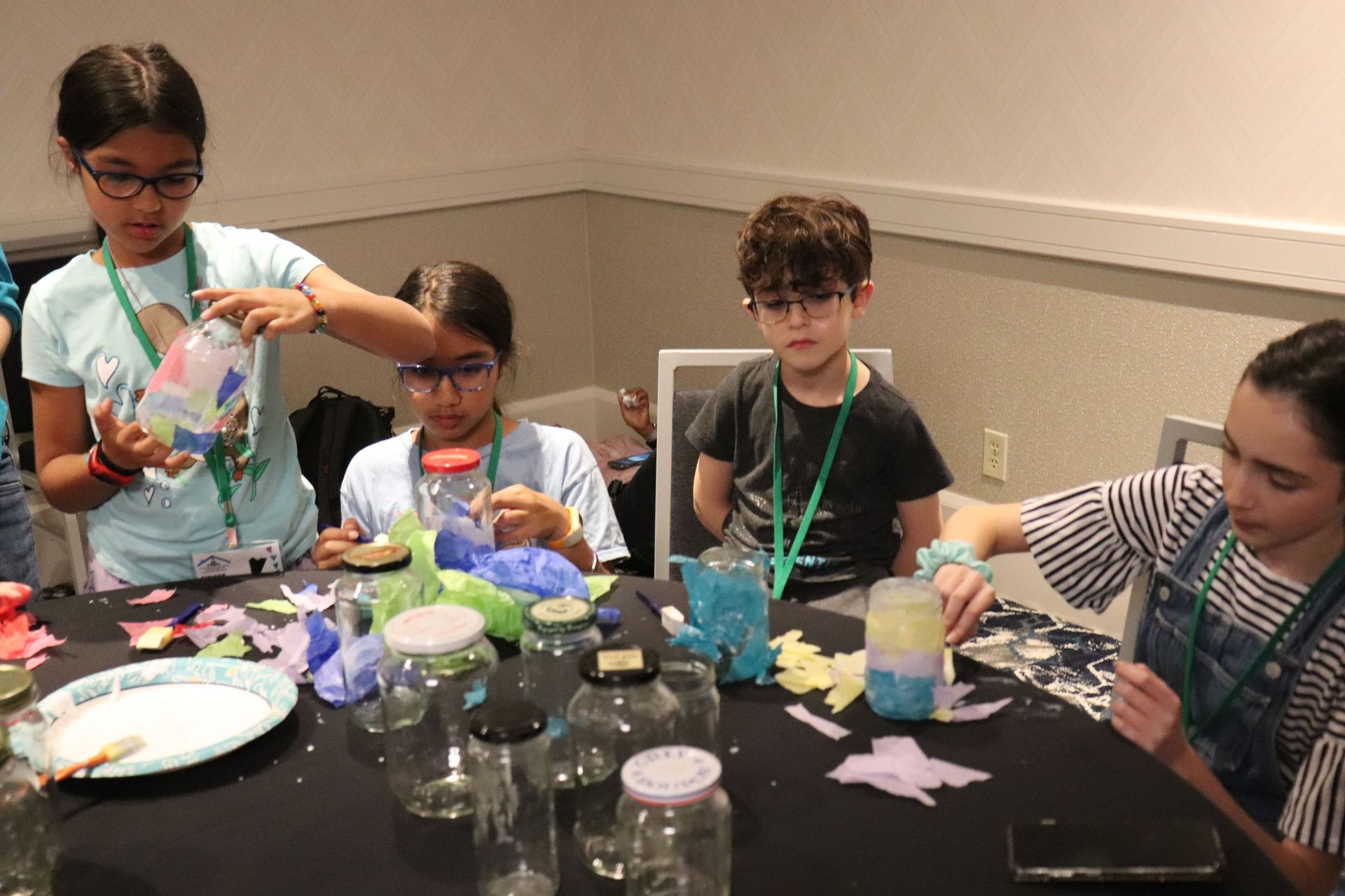 A group of children are sitting at a table making crafts.