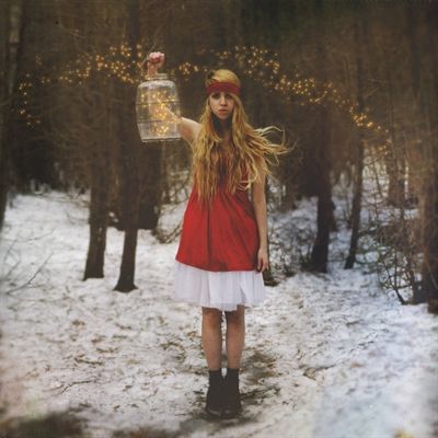 A woman in a red dress is holding a lantern in the snow