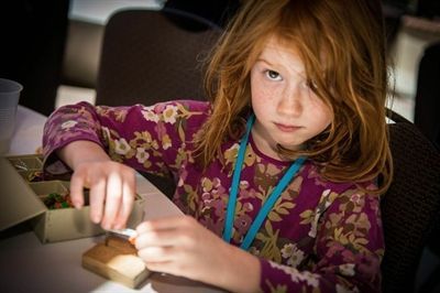 A little girl is sitting at a table playing with a toy.