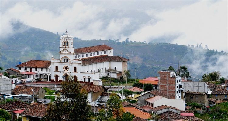 A church is sitting on top of a hill in the middle of a small town.