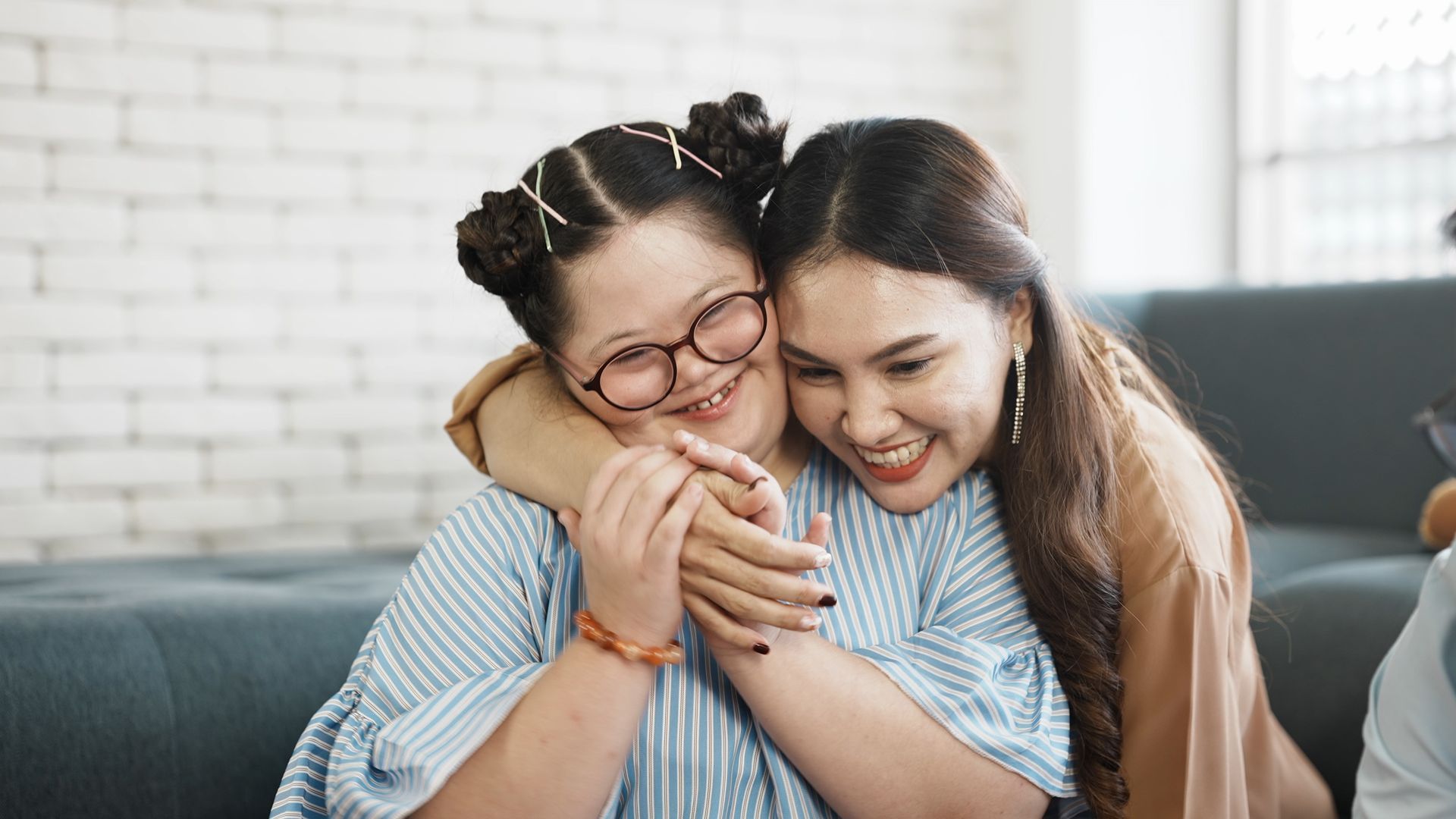 Two women are hugging each other on a couch.