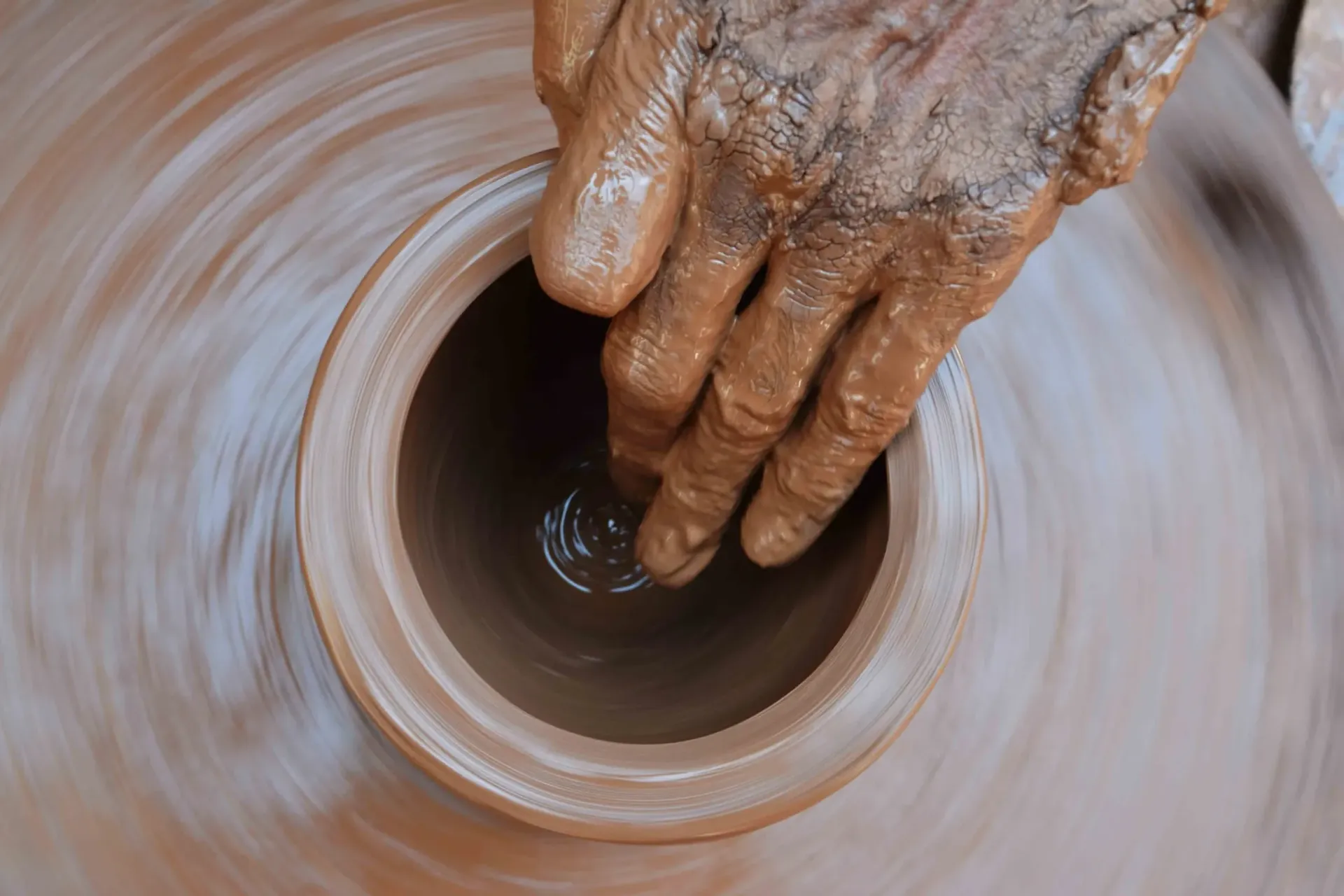 A person is making a pot on a pottery wheel.