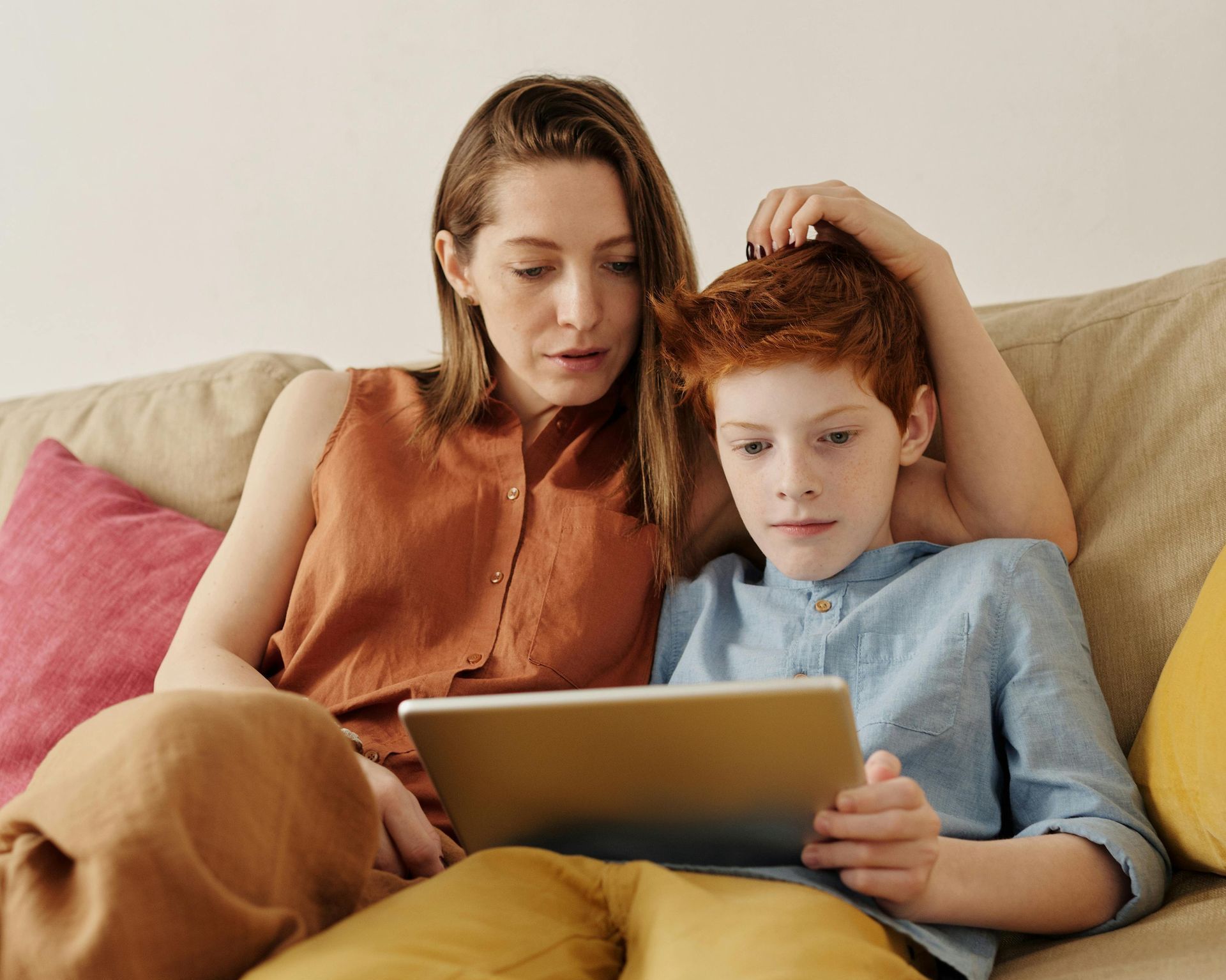 California homeschooling parent and child learning together on a tablet at home.