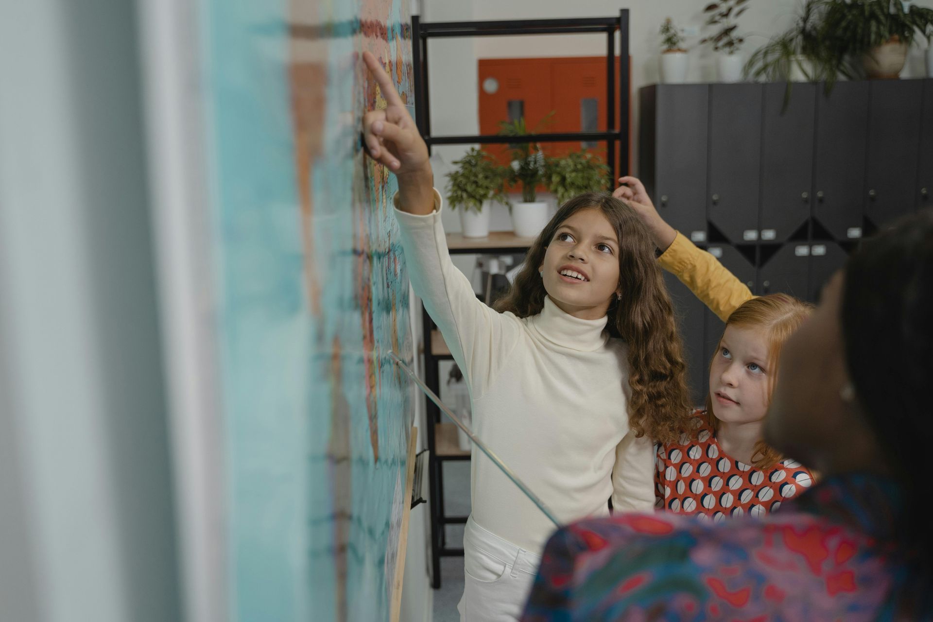 Homeschooled children in California exploring geography using a map on a whiteboard.