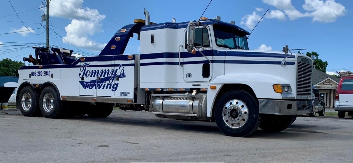 A white and blue tow truck is parked in a parking lot.