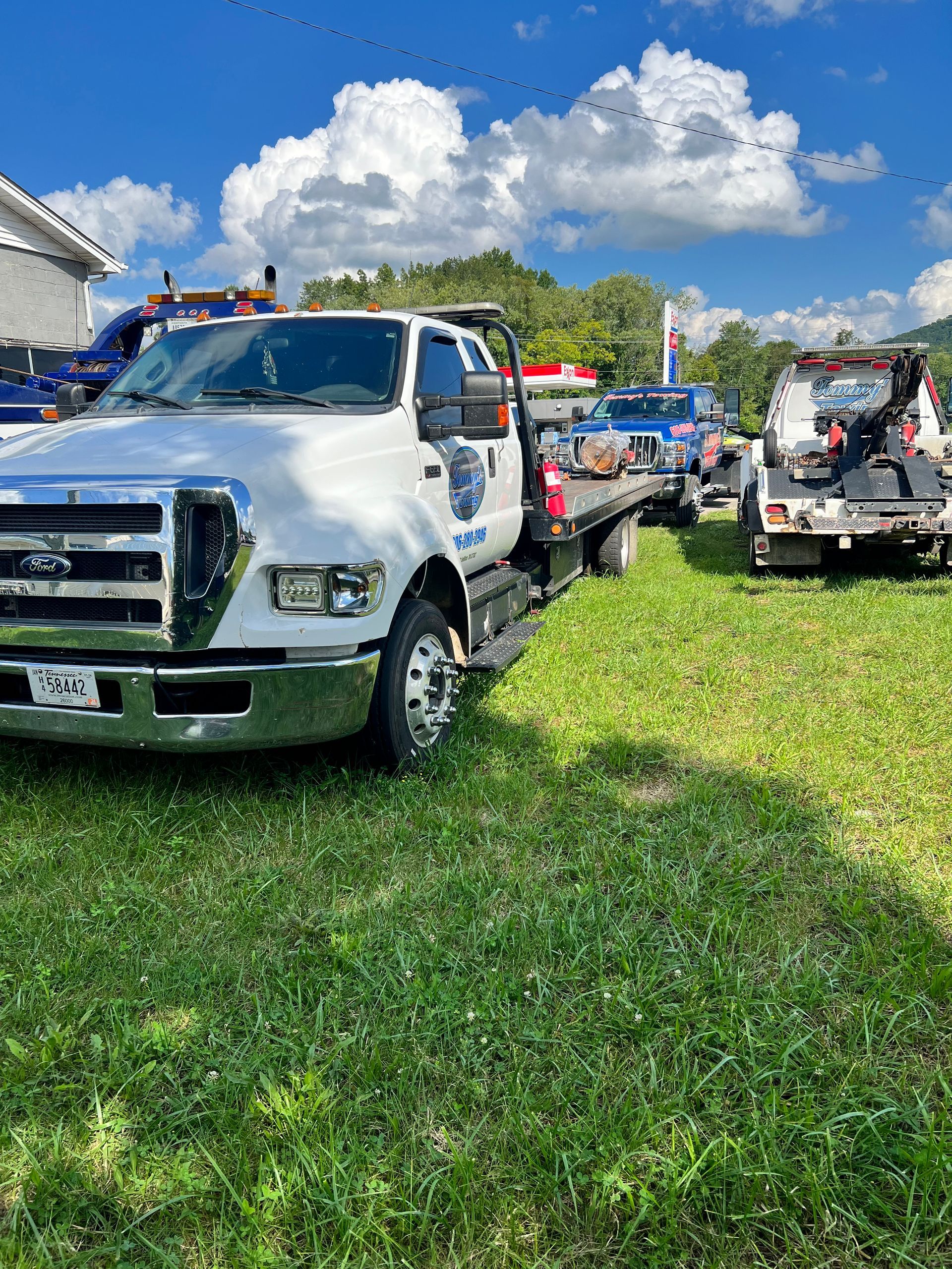 A white tow truck is parked in a grassy field.