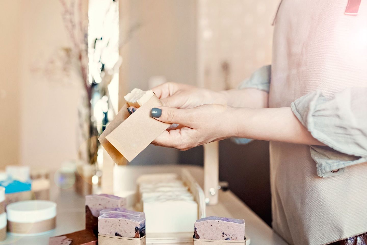 Person packaging soap bars, hands holding brown label, soaps on display.