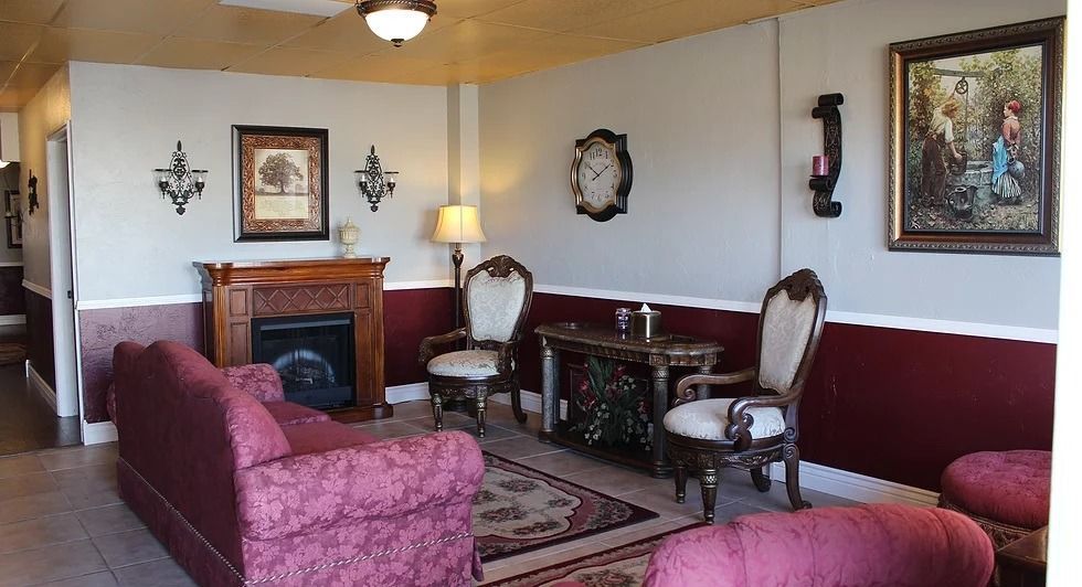 Living room with burgundy accents, fireplace, antique furniture, and decorative wall art.