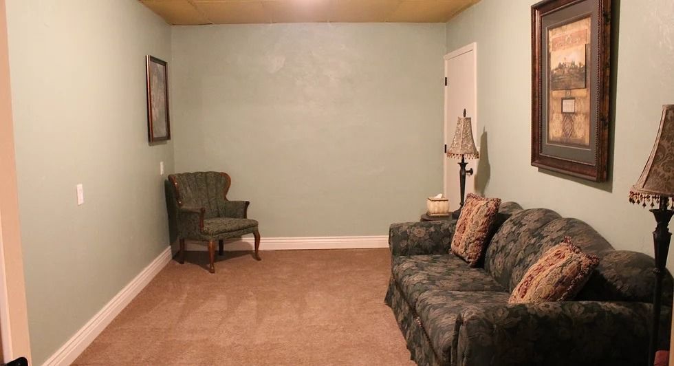 Small room with green walls, brown carpet, and a sofa with patterned pillows.