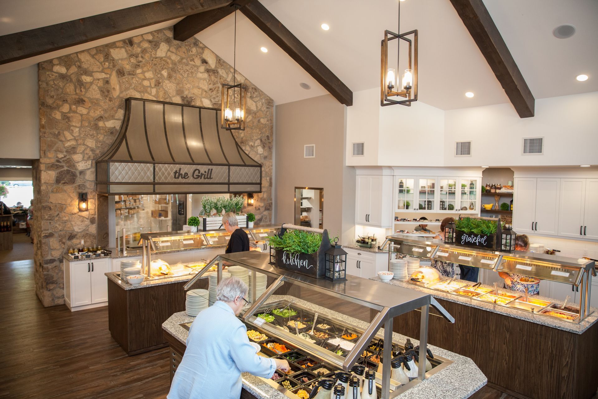 A woman is standing at a buffet line in a restaurant.