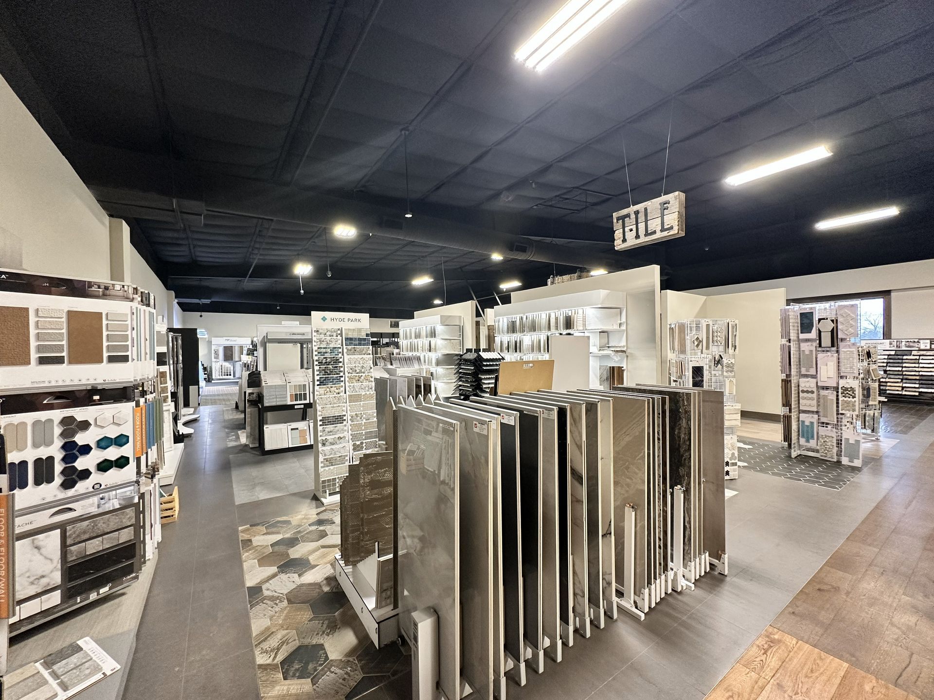 A showroom displaying tile and stone flooring samples on rows of vertical racks under bright ceiling lights.