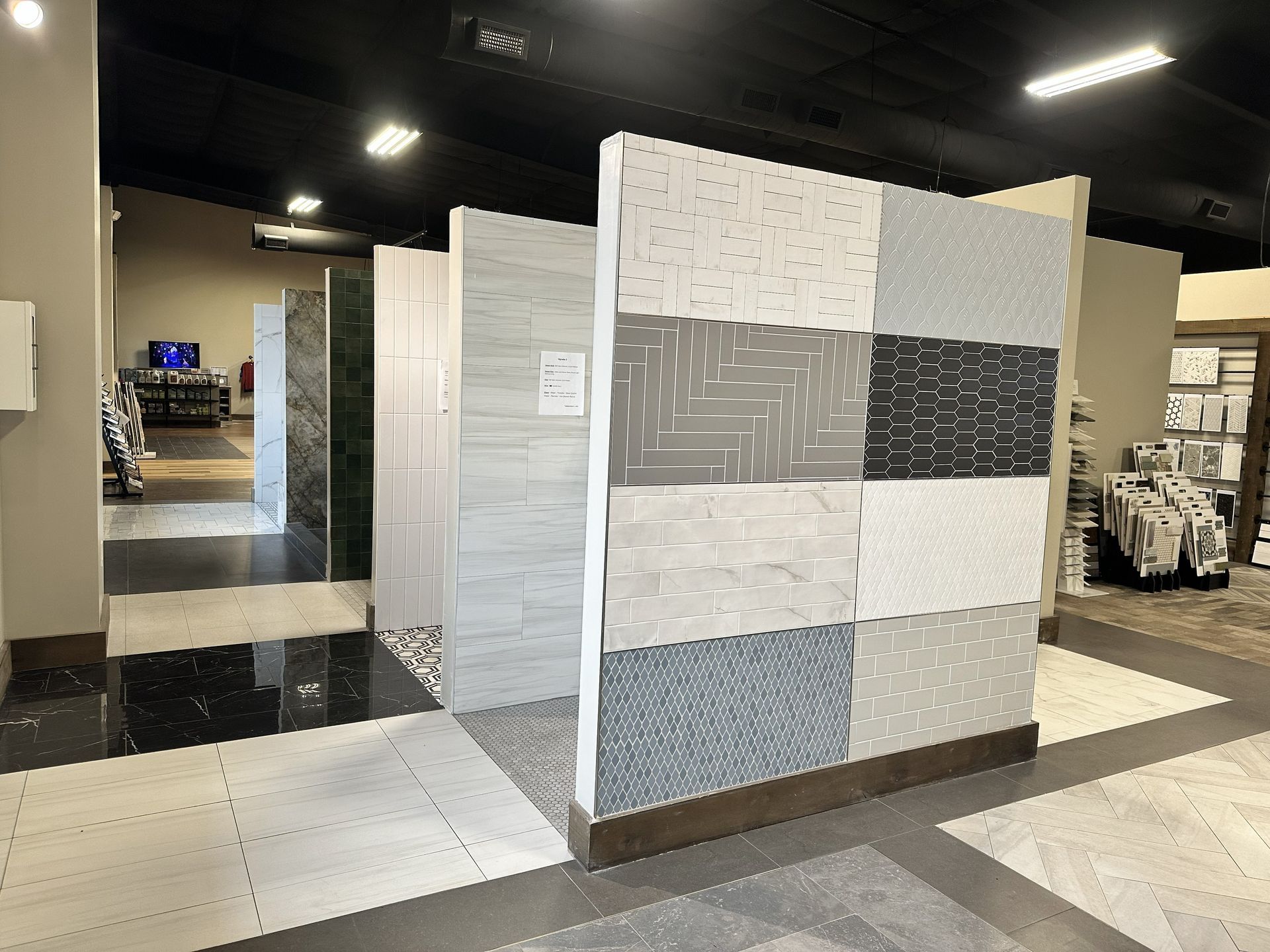 A showroom floor displays various tile and flooring samples on vertical panels and the ground.