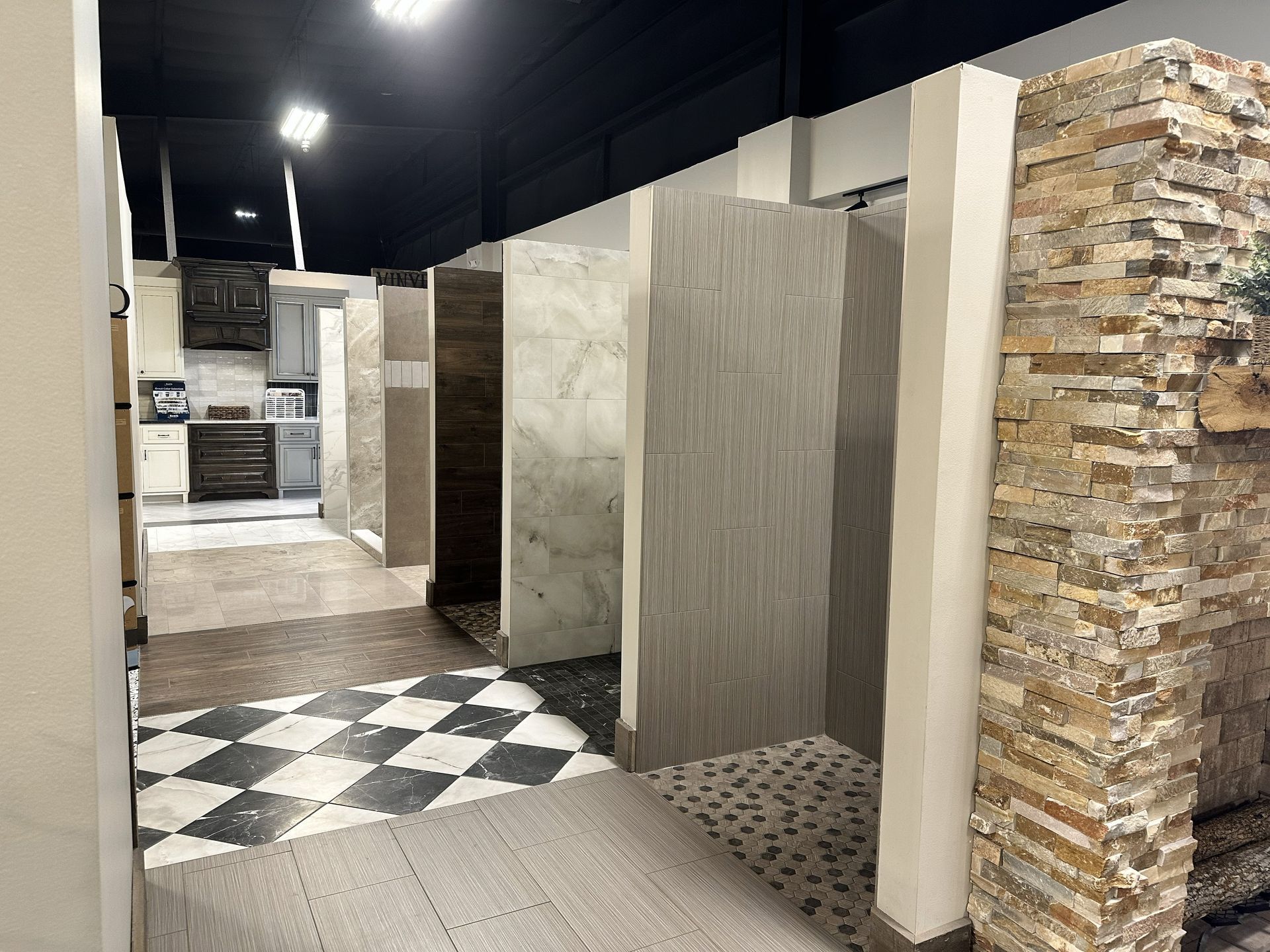 A showroom display featuring several side-by-side shower stalls with various tile styles and flooring materials.