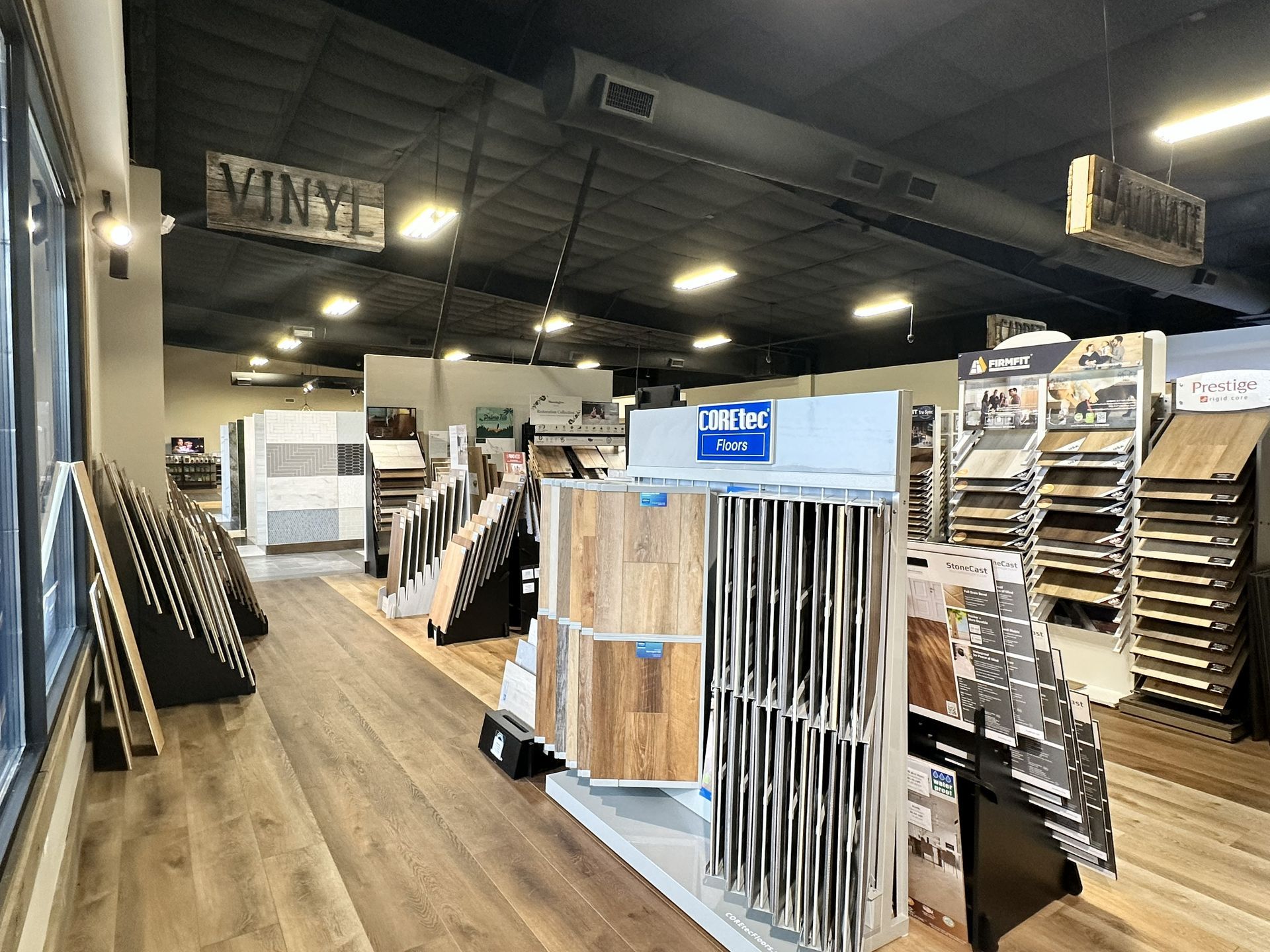 A flooring store showroom featuring numerous displays of vinyl planks and wood-look tiling samples.