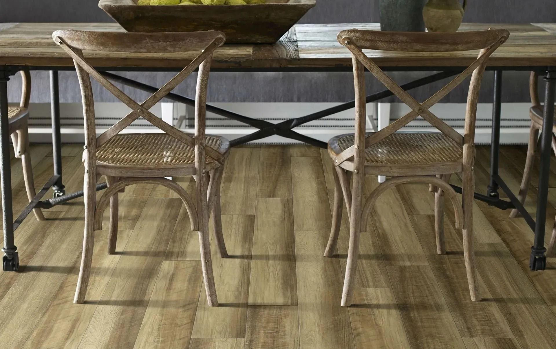 Two wooden cross-back chairs with woven seats positioned at a rustic dining table on a light wood-look floor.