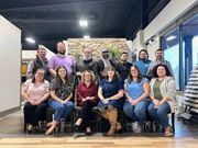 A modern kitchen featuring gray cabinets, white countertops, subway tile backsplash, a black refrigerator, and wood floors.