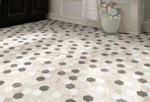 A bathroom floor tiled in a repeating pattern of white, beige, and dark gray hexagons, viewed from a slightly high angle.