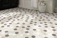 A bathroom floor tiled in a repeating pattern of white, beige, and dark gray hexagons, viewed from a slightly high angle.