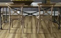 Two light wood cross-back chairs pulled up to a rustic wooden dining table on hardwood flooring.