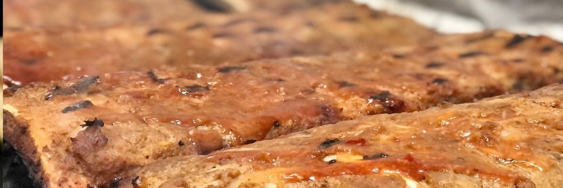 Close-up van gekruide, geglazuurde ribben die op de grill worden bereid, met zichtbare grillstrepen en saus.