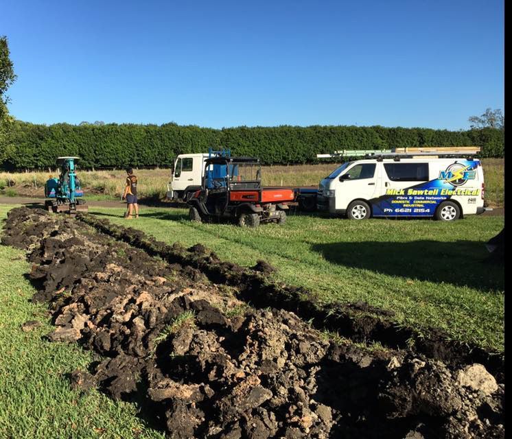 A Van is Parked in a Grassy Field Next to a Tractor — Mick Sawtell Electrical Pty Ltd in South Lismore, NSW