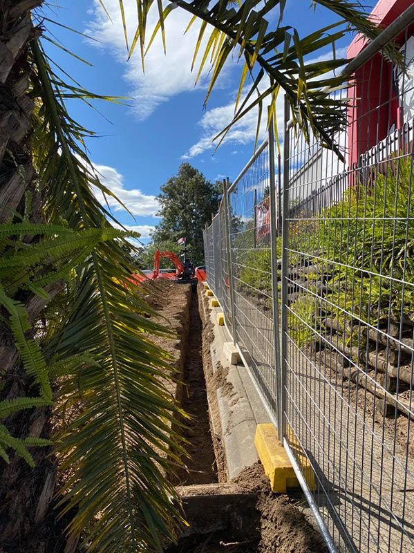 A Construction Site With a Fence and a Palm Tree in the Foreground — Mick Sawtell Electrical Pty Ltd in South Lismore, NSW