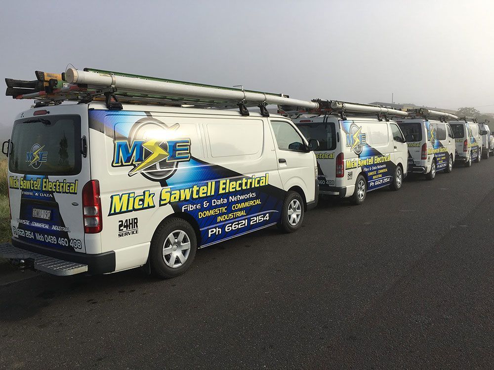 A Row of Electrical Vans Are Parked on the Side of the Road — Mick Sawtell Electrical Pty Ltd in South Lismore, NSW