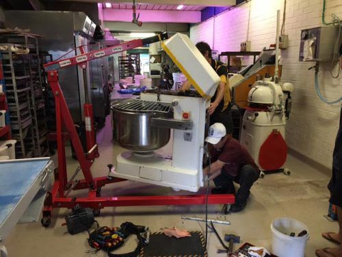 A Group of People Are Working on a Mixer in a Kitchen — Mick Sawtell Electrical Pty Ltd in Grafton, NSW