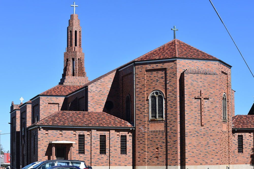 A Large Brick Church With a Cross on Top of It — Mick Sawtell Electrical Pty Ltd in Casino, NSW