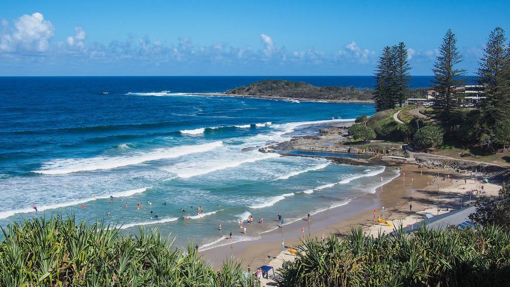A Beach With a Lot of People on It and Waves Crashing on the Shore — Mick Sawtell Electrical Pty Ltd in Yamba, NSW
