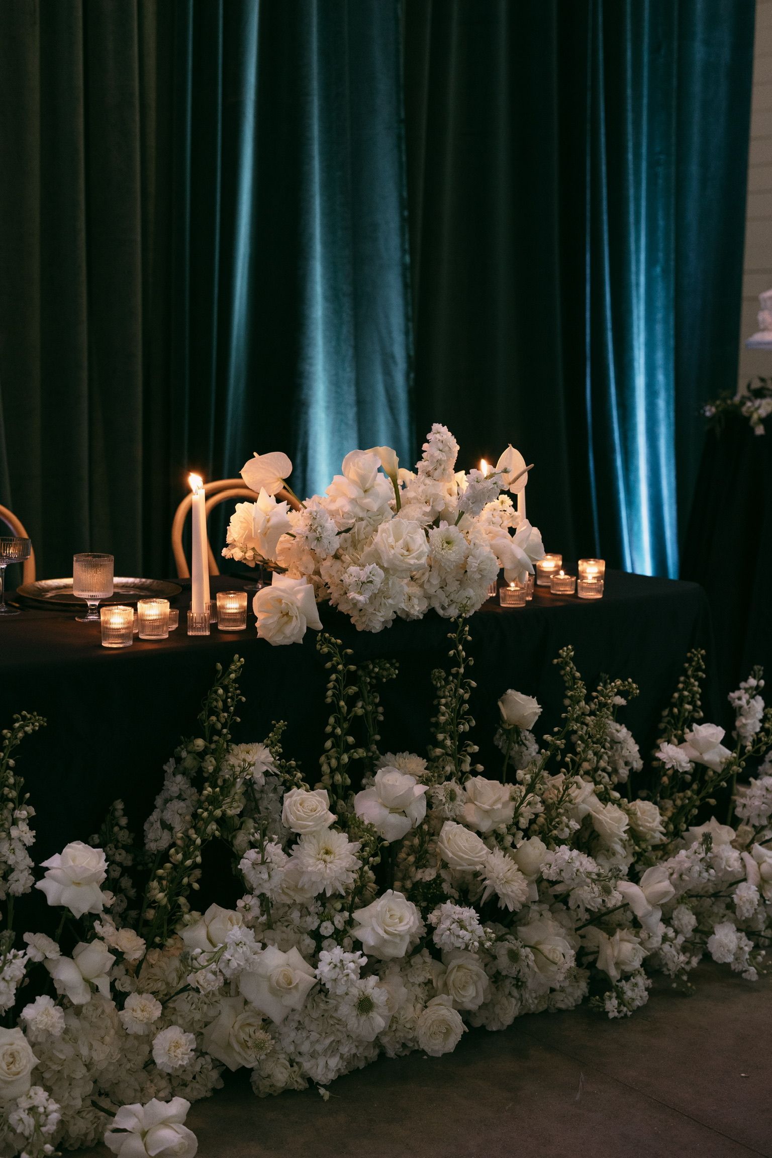 A long table with white flowers and candles on it.