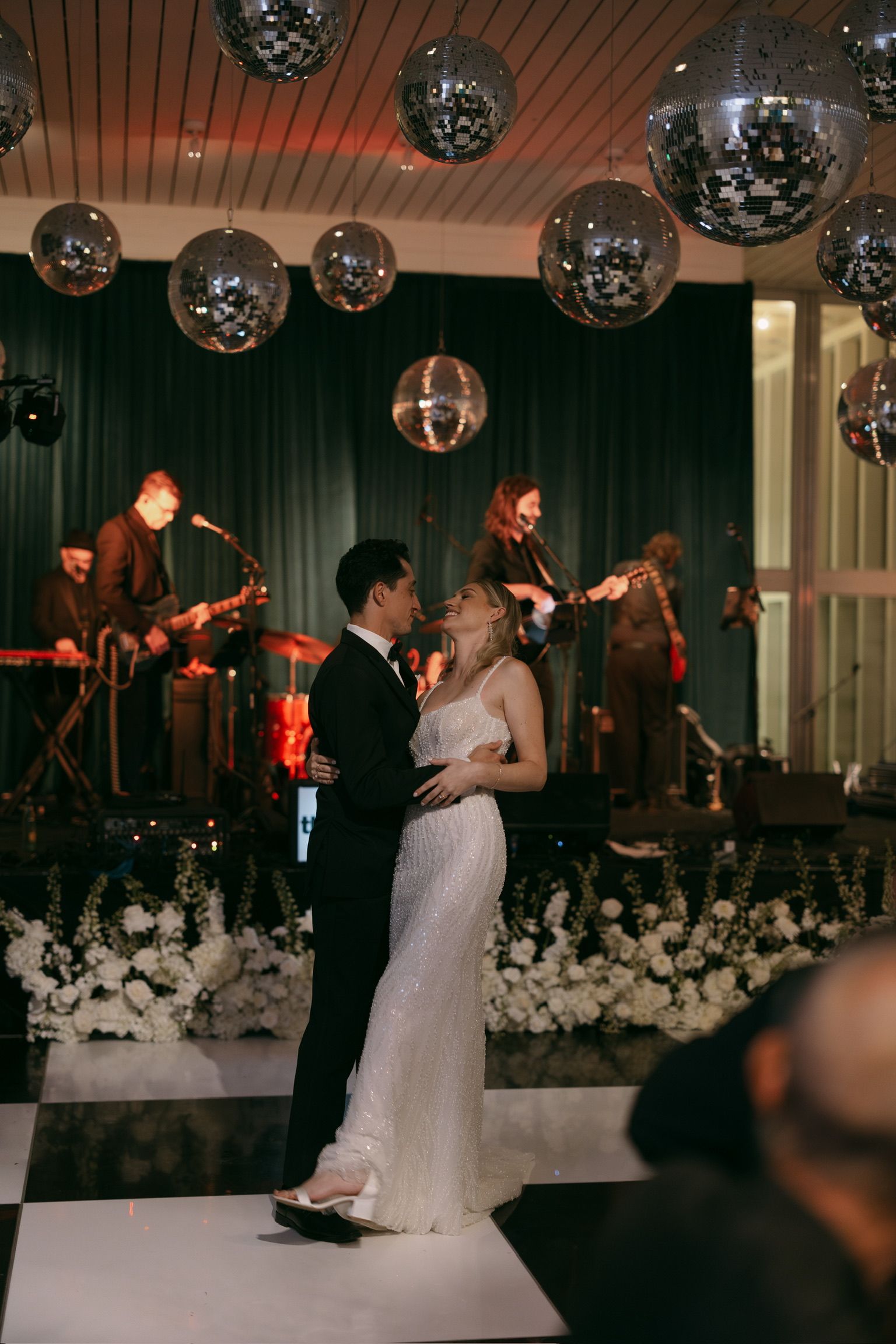 A bride and groom are dancing on a dance floor in front of a band.