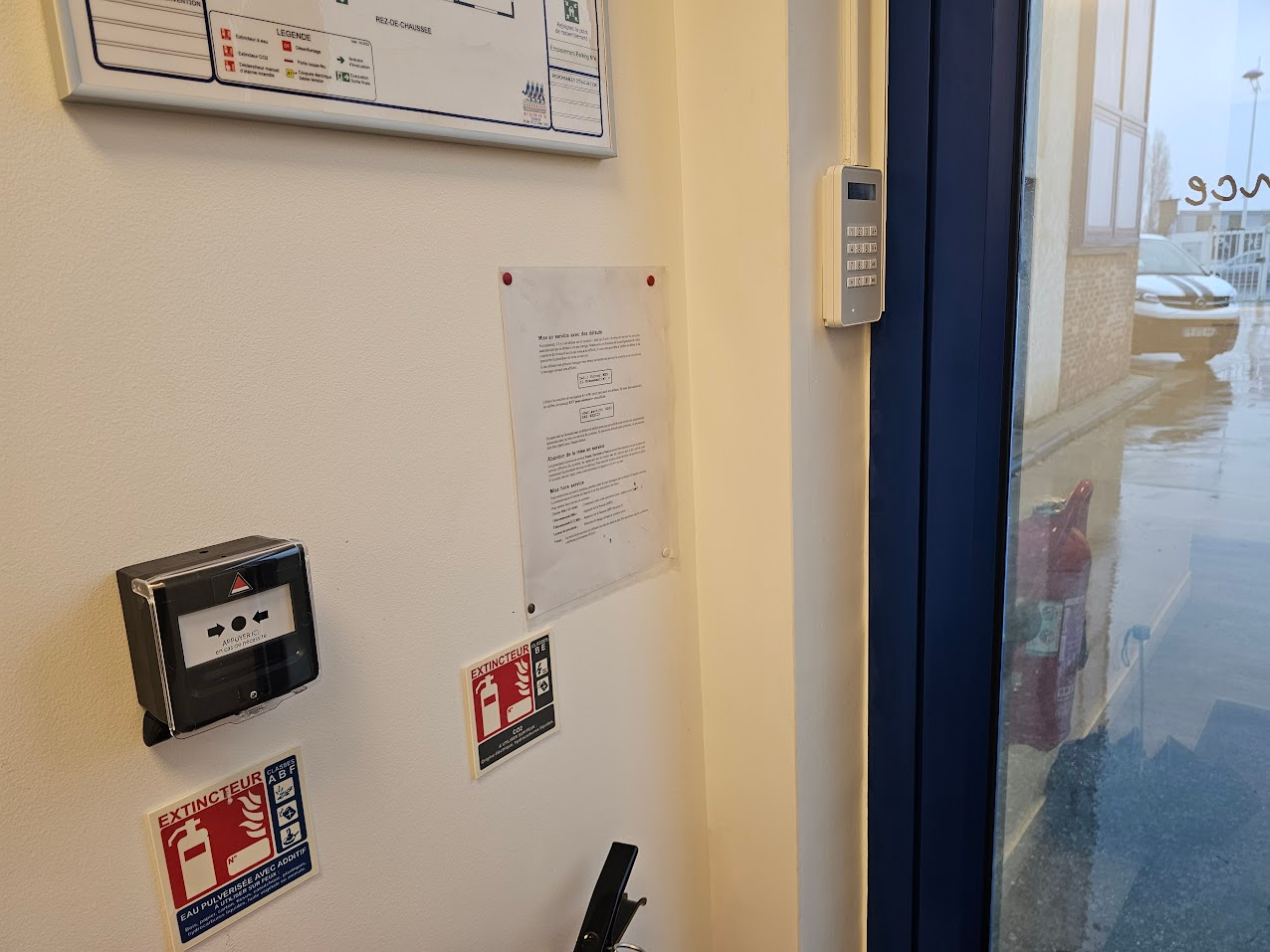 Une pièce avec une porte et une alarme incendie sur le mur