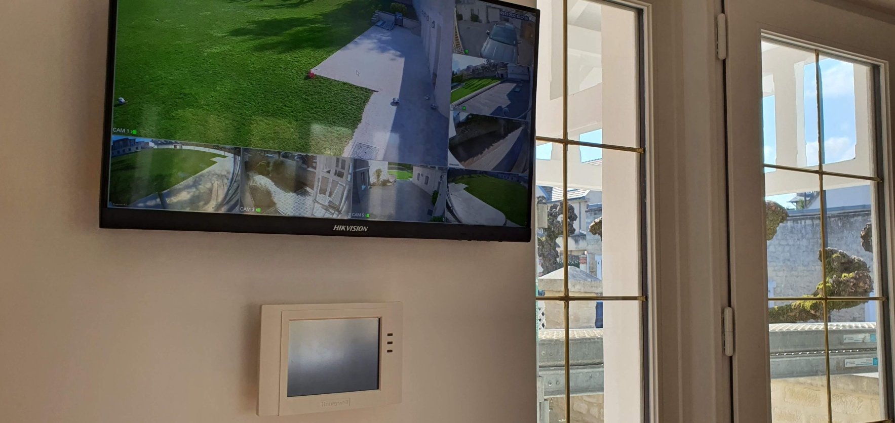 Une télévision est accrochée sur un mur à côté d'une fenêtre.