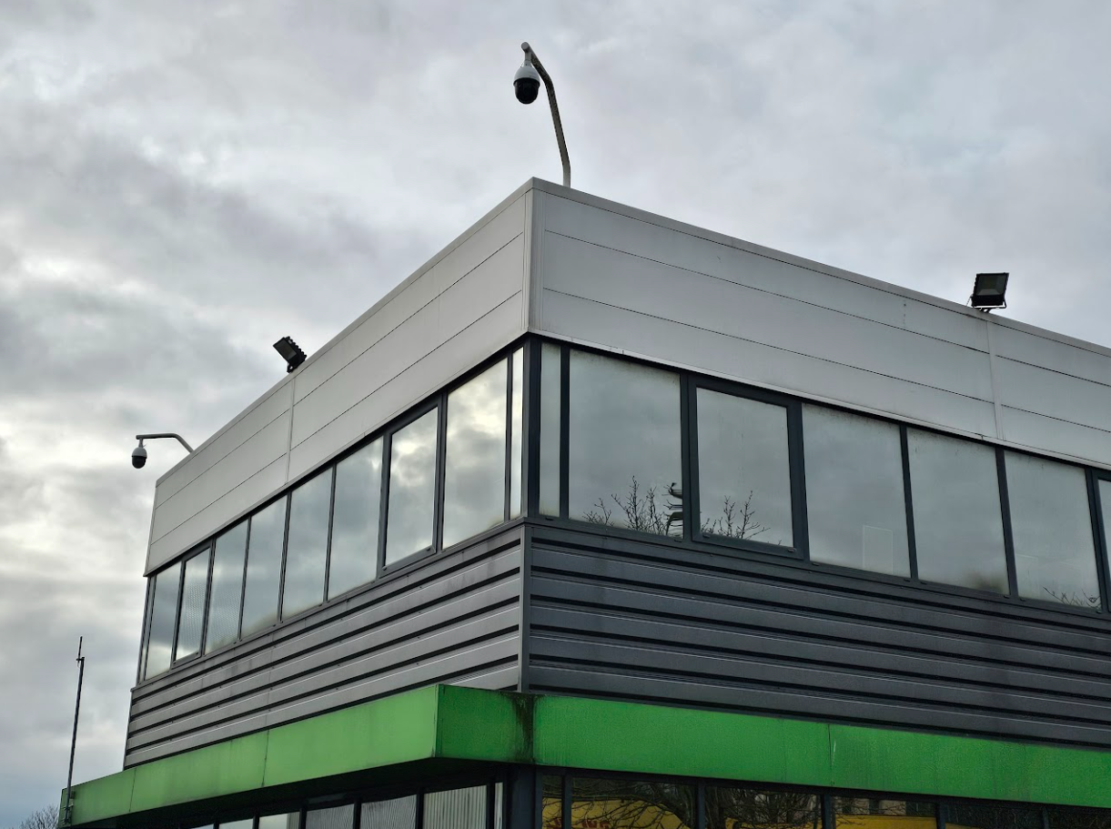 Un grand bâtiment avec un toit vert et beaucoup de fenêtres